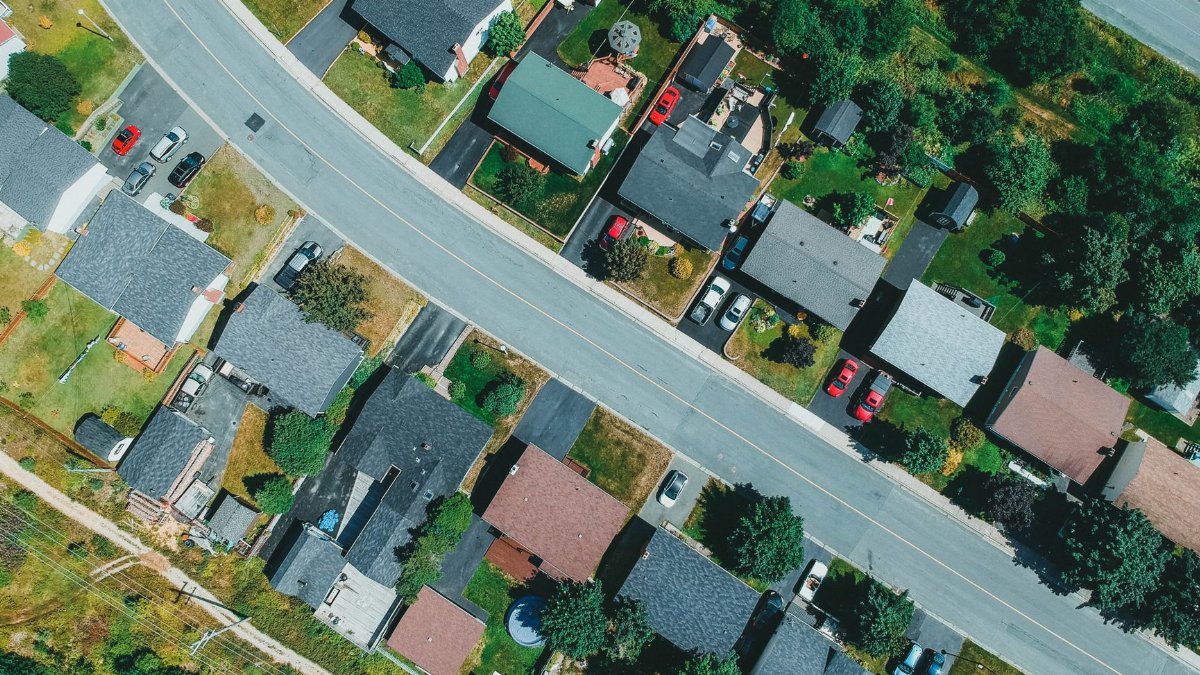 Aerial drone shot capturing suburban neighborhood houses and streets with greenery.