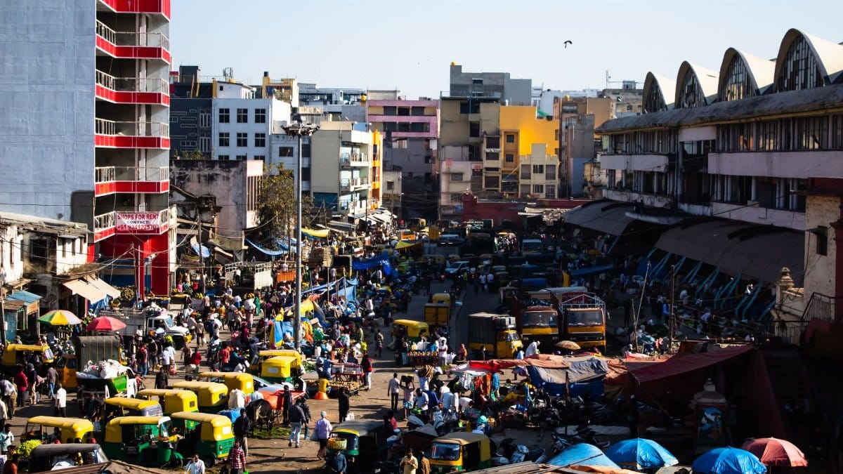 Bustling street scene in Bengaluru, India with colorful vehicles and vibrant market activity.