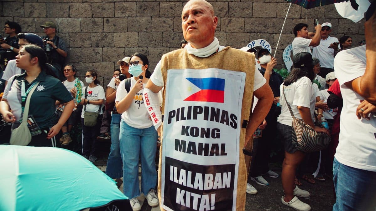 A protest in Manila with a man wearing a patriotic slogan, highlighting national unity and activism.