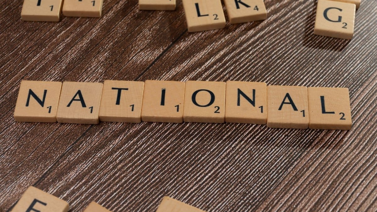 Close-up of scattered Scrabble tiles on a wooden table spelling 'National'.