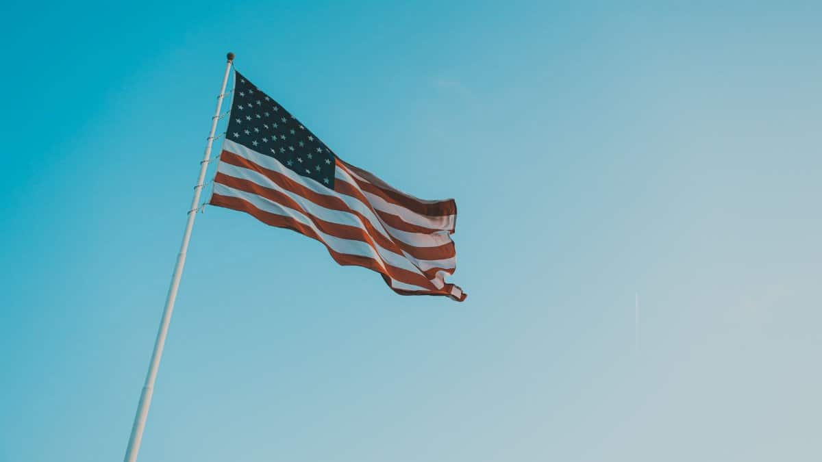 A low angle shot of the American flag waving against a clear blue sky, symbolizing patriotism.