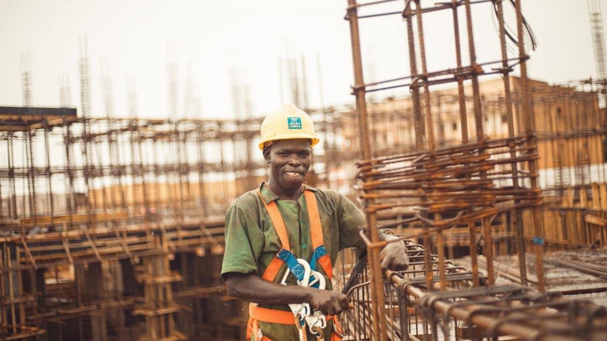 Smiling construction worker wearing a helmet at a site in Kitgum Matidi, Uganda.