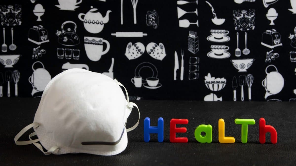 A face mask and colorful health text on a kitchen-themed background.
