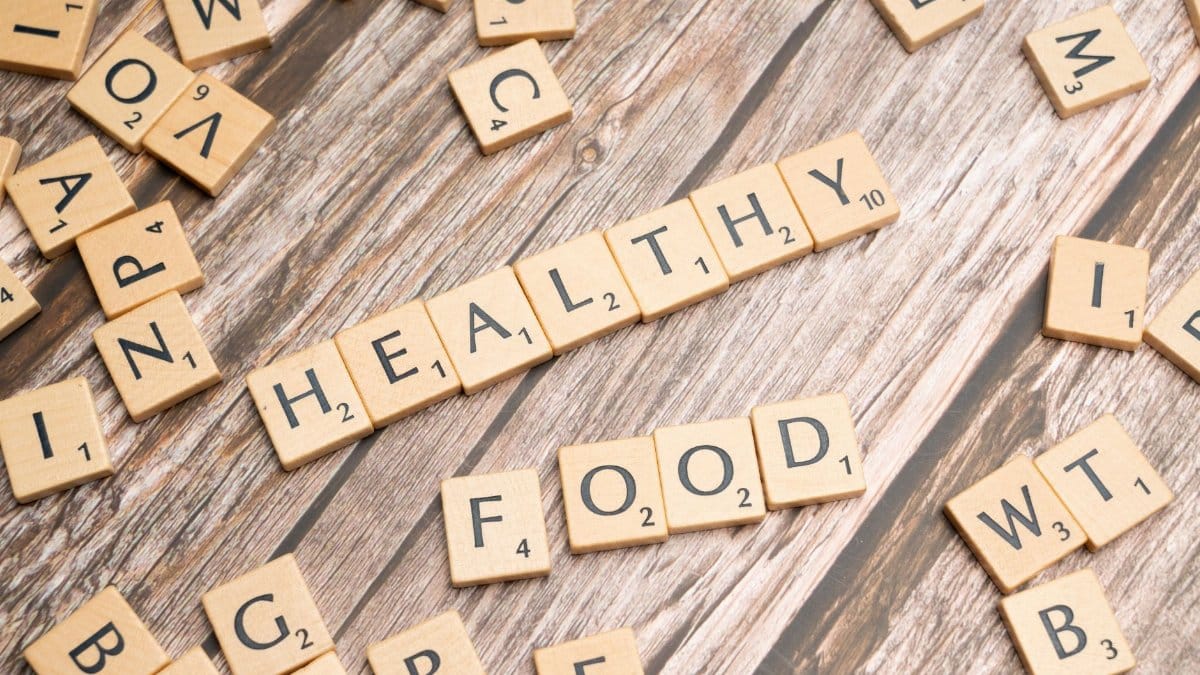Wooden tiles spelling 'healthy food' on a wooden background creating a natural and organic theme.