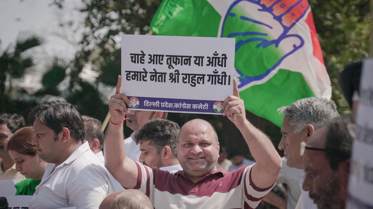 Crowd holding a political banner with a flag at a demonstration in India.