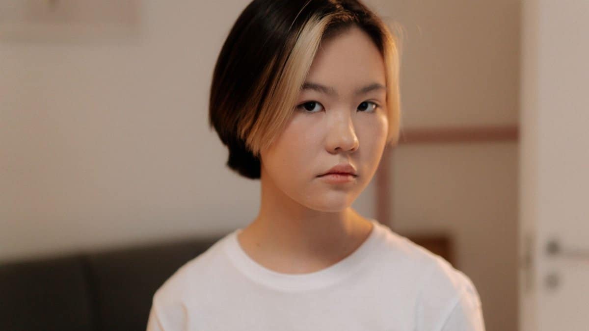 Portrait of a young woman with short hair in a white shirt, indoors.