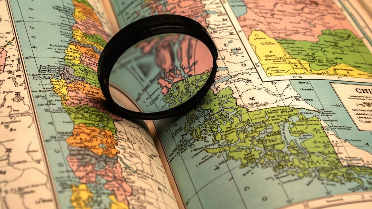 A close-up of a colorful world map with a magnifying glass highlighting details.
