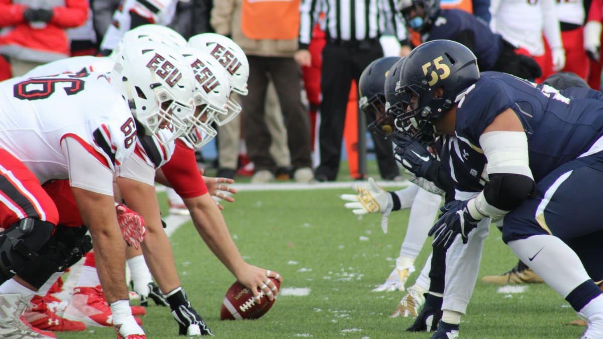 Rival football teams face off at the start of an action-packed game on the field.