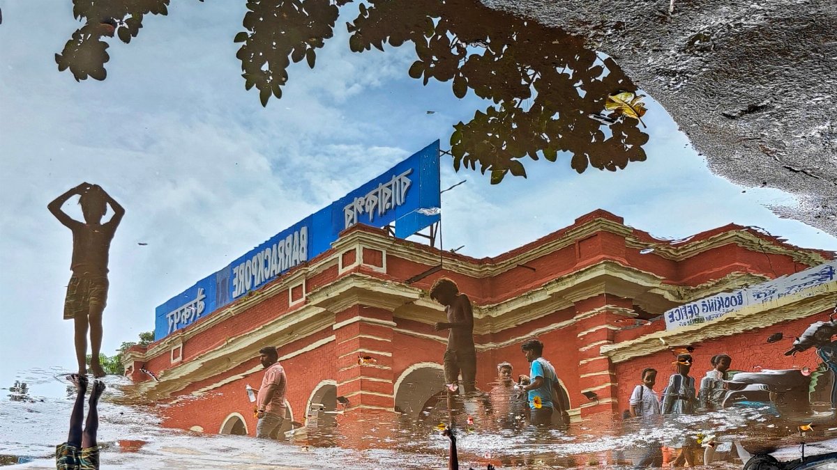 Reflections of an iconic building in Kolkata captured in a puddle, creating a vibrant urban scene.