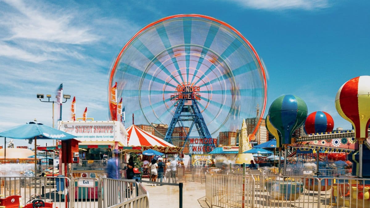 Vibrant scene of Ferris wheel and attractions at Coney Island, New York.