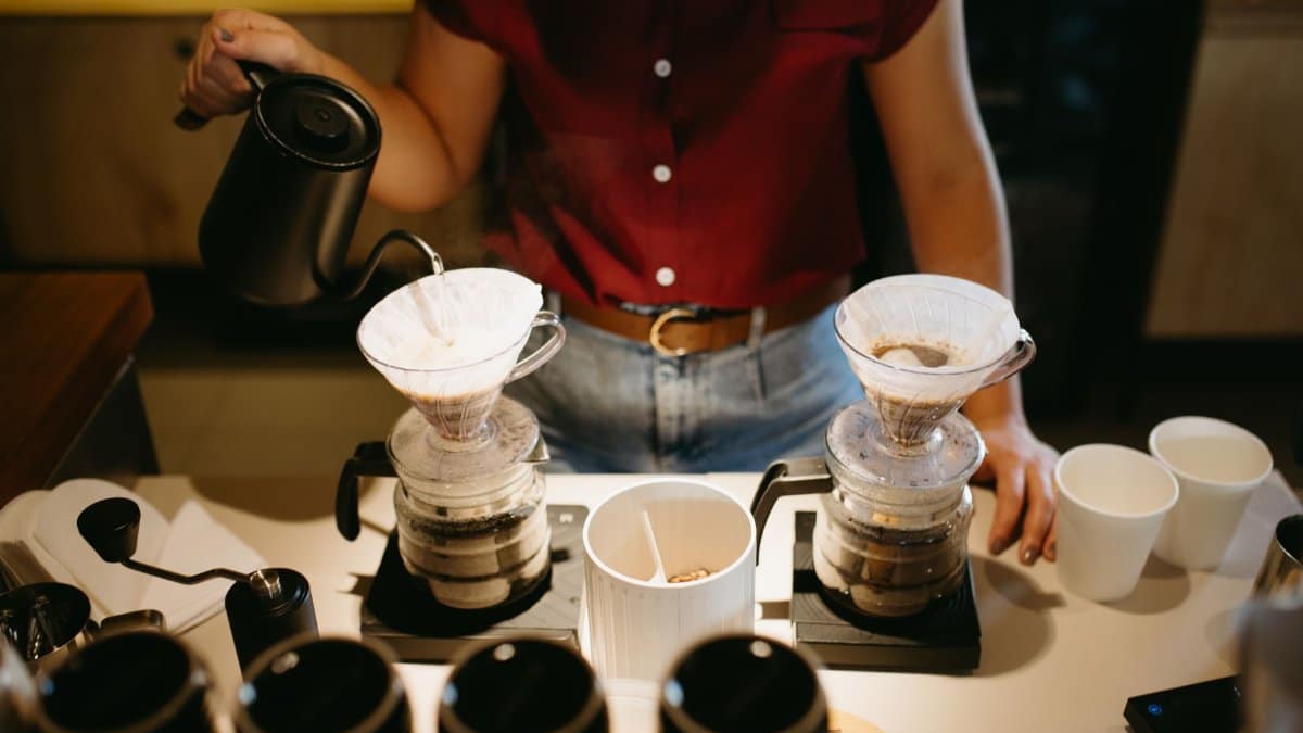 Barista preparing coffee using pour-over method in a café setting, capturing the artisanal brewing process.