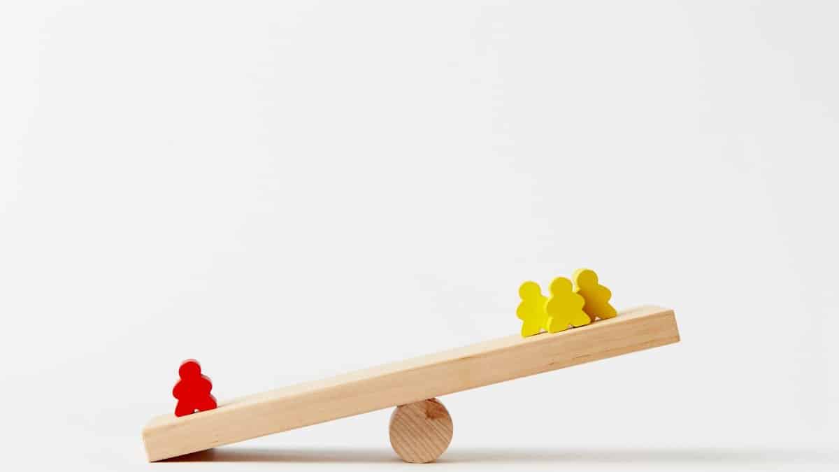 Wooden seesaw toy with colorful figures illustrating balance and play in a minimalist style.