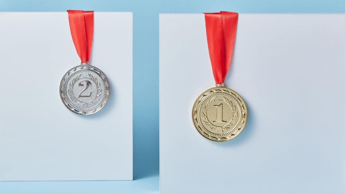 Gold and silver medals with red ribbons against a blue backdrop representing achievement and success.