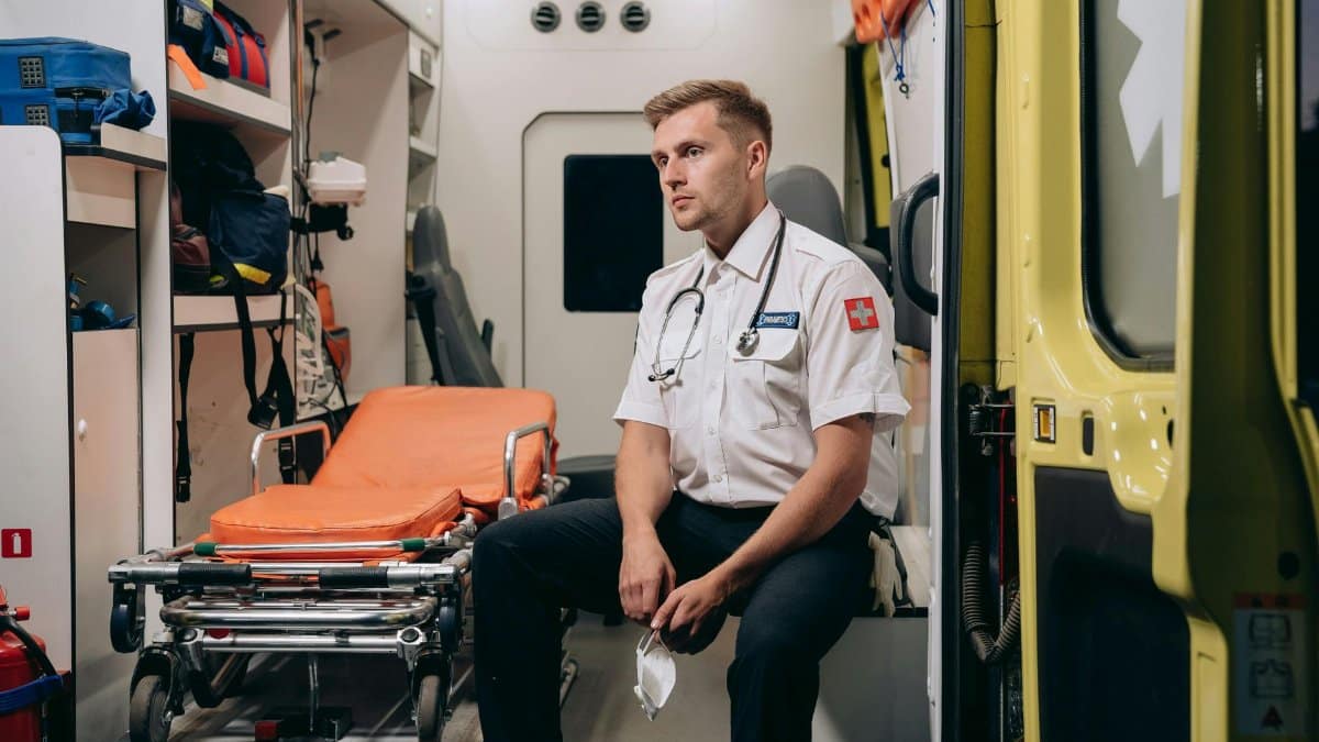 A paramedic sits in an ambulance van interior, exemplifying readiness for emergency medical services.