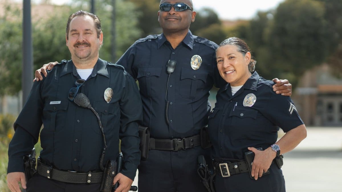 Diverse group of police officers in uniform smiling together outdoors.