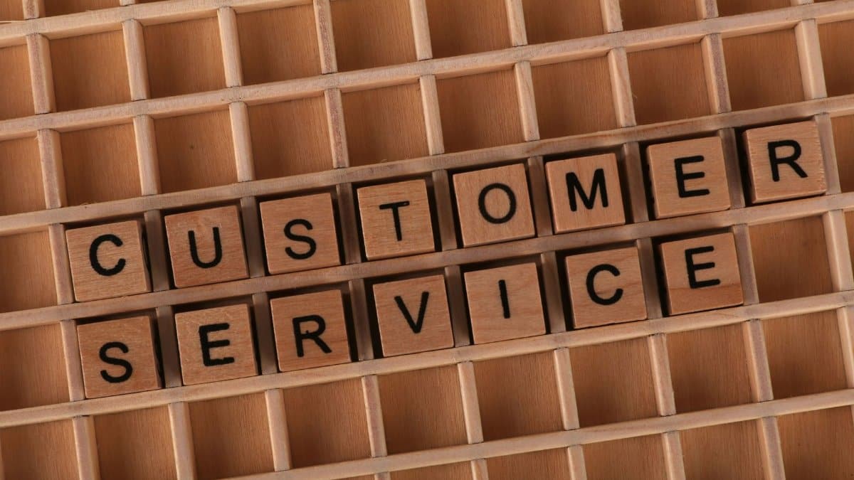 Wooden blocks forming the phrase 'Customer Service' placed inside a wooden grid, symbolizing support and assistance.