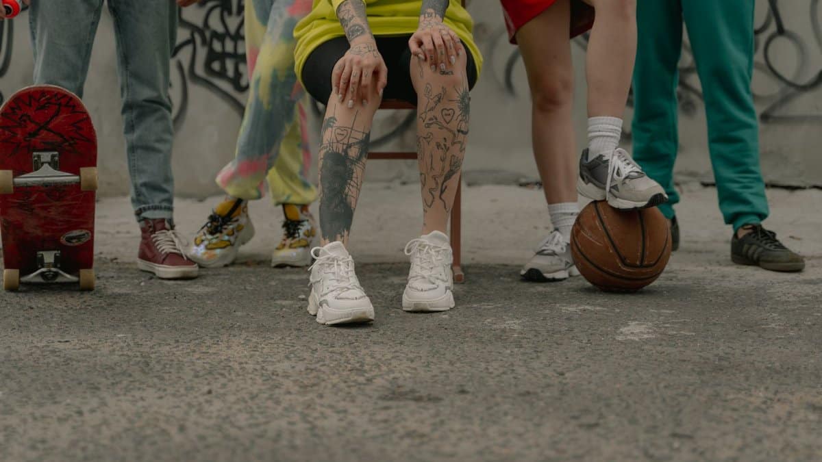 A group of stylish young adults with a basketball and skateboard in an urban setting.