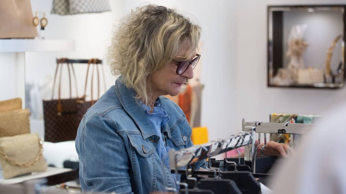 Elderly woman exploring fashion items in a boutique store, showcasing style and independence.