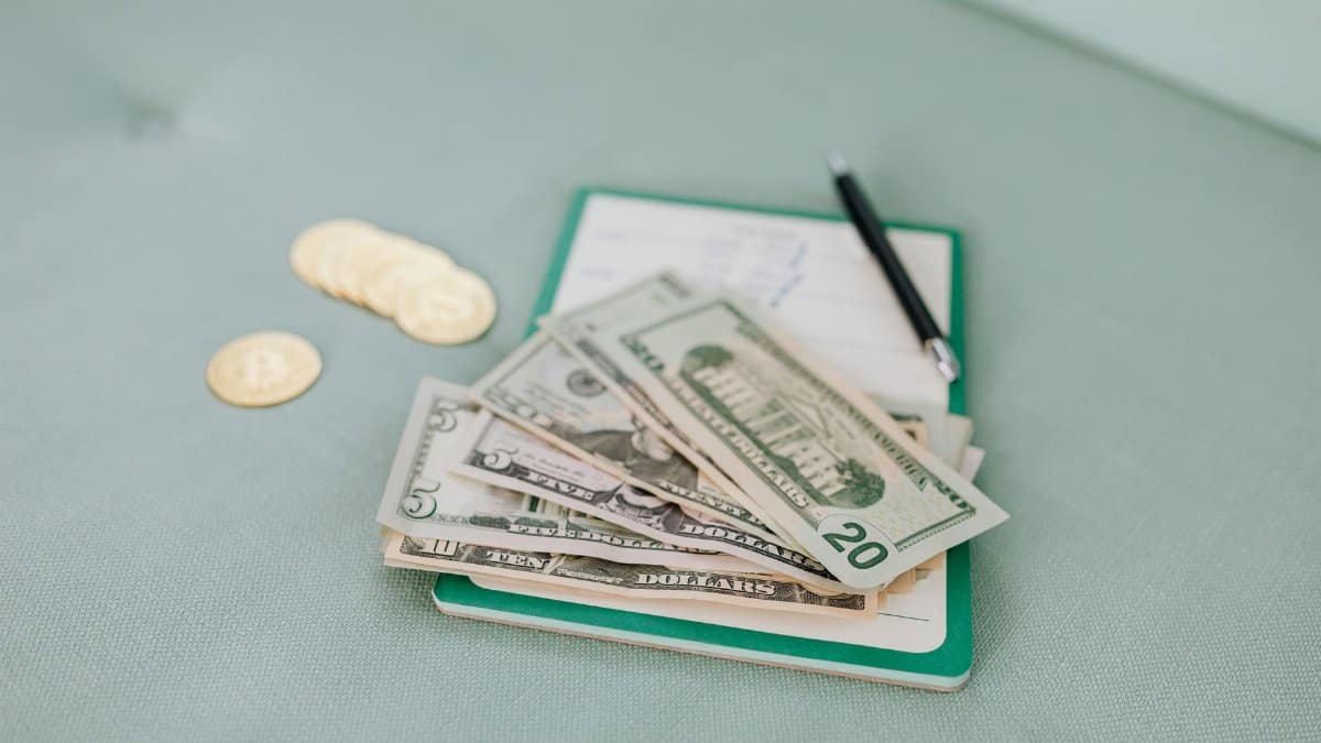 Close-up of American dollar bills and coins on a journal with a pen, representing budget planning.