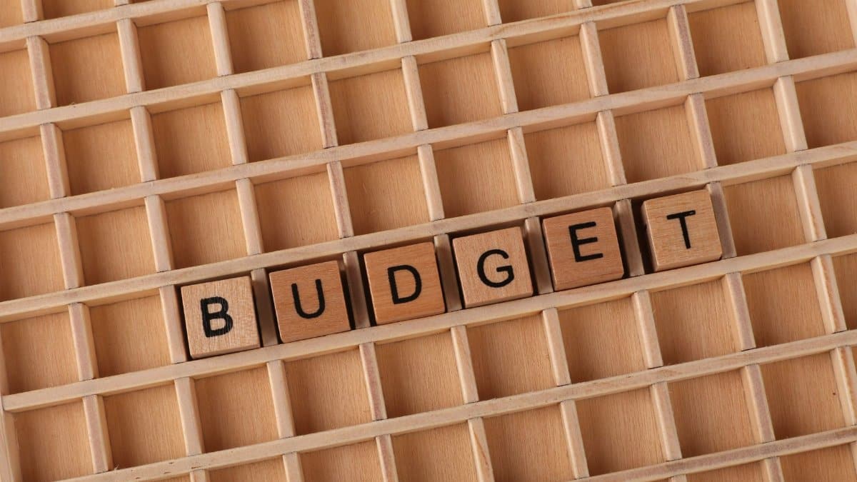 Wooden letter tiles spelling 'budget' on a wooden grid background, symbolizing finance and planning.