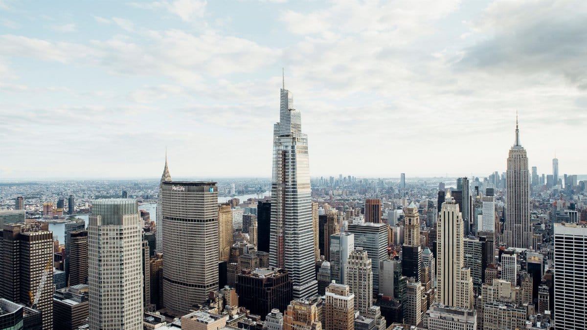 Drone view of modern high rise houses and empire state building located against cloudy sky in downtown of New York city