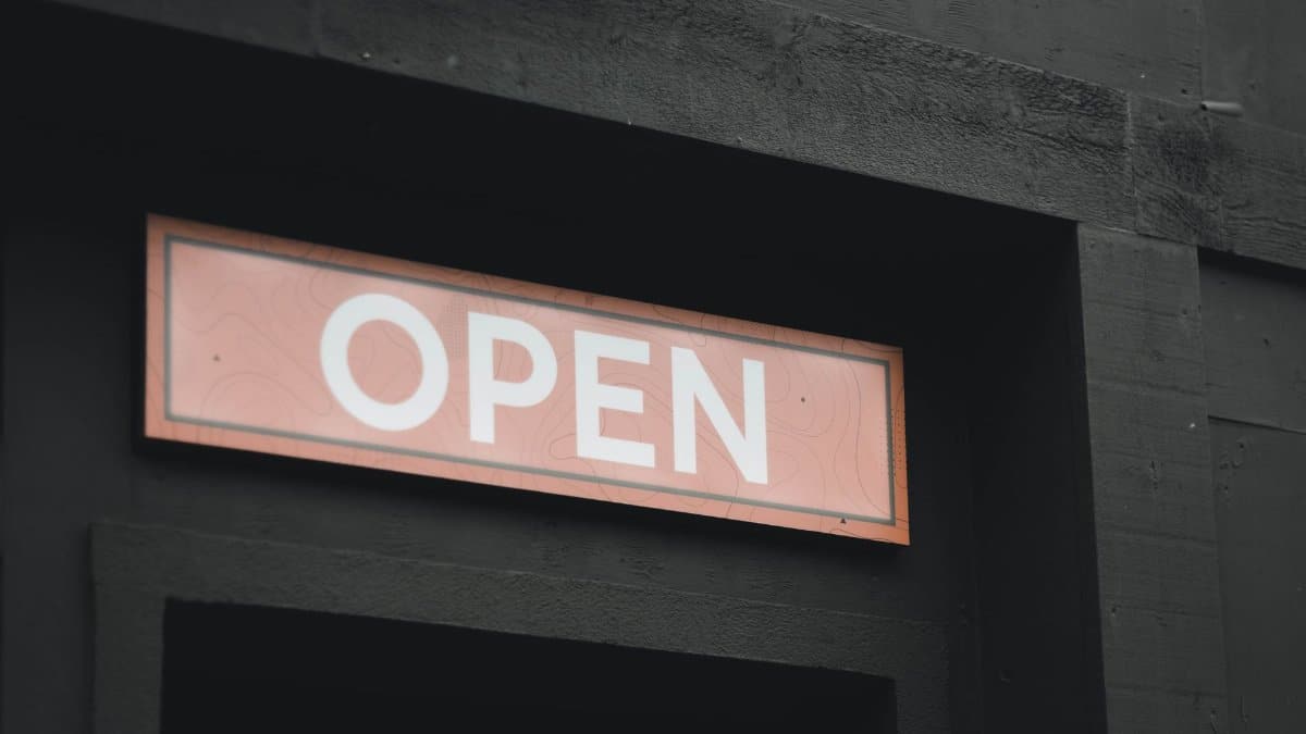 A striking image of an illuminated 'Open' sign on a dark building exterior, perfect for business themes.