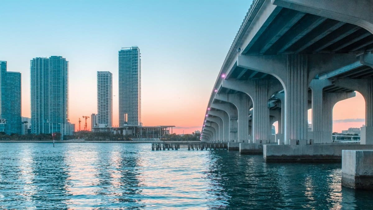 Stunning view of Miami Beach's skyline with a bridge at sunset, reflecting on the water.