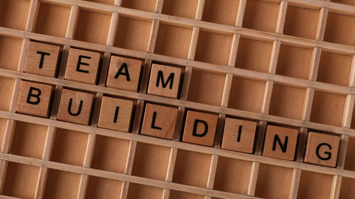 Wooden letter tiles spelling 'Team Building' on a grid surface to symbolize collaboration.