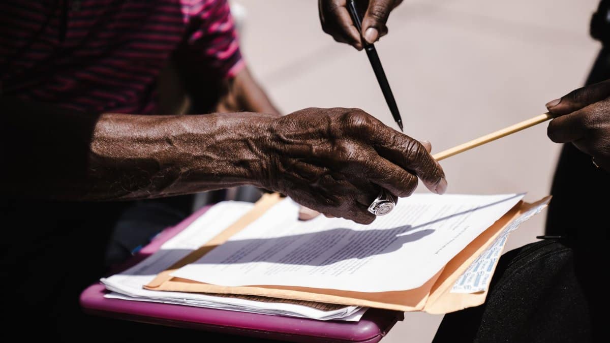 Close-up of hands exchanging documents with pens outdoors. Business agreement concept.