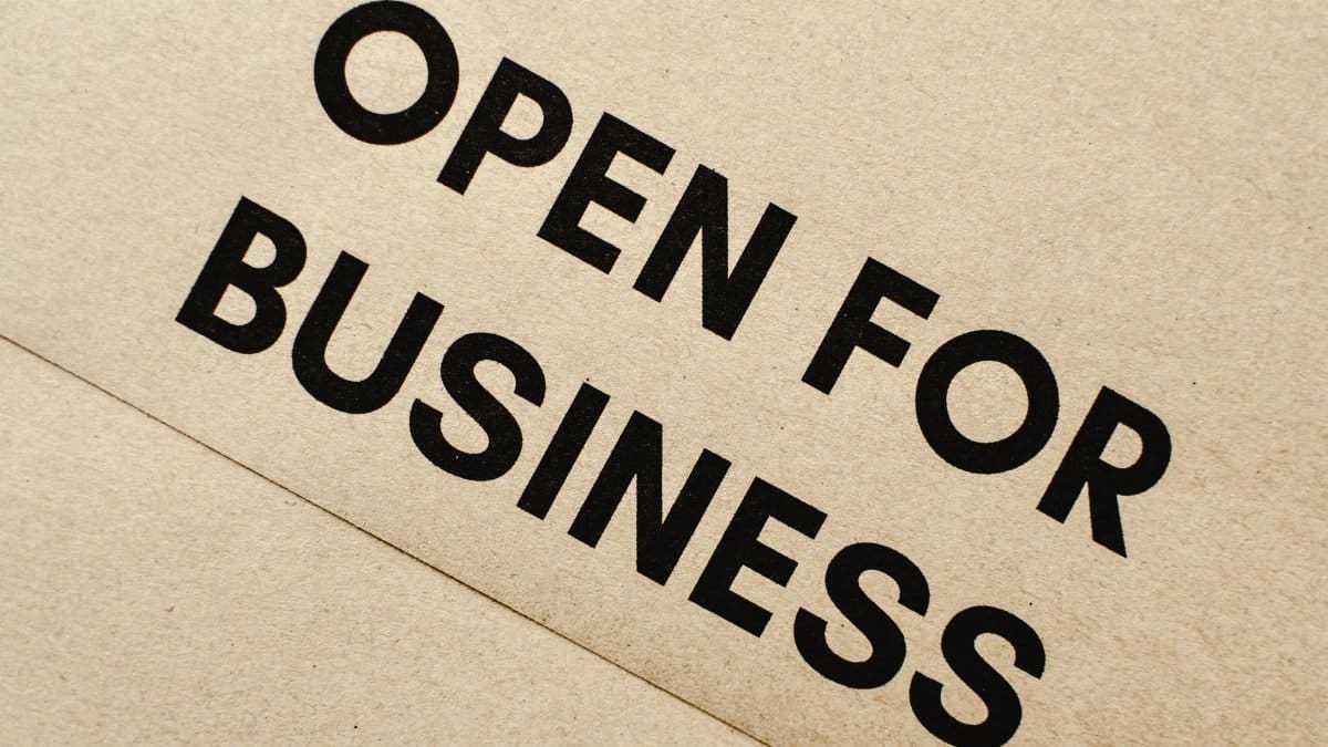 Close-up of an 'Open for Business' sign on a textured brown paper background.