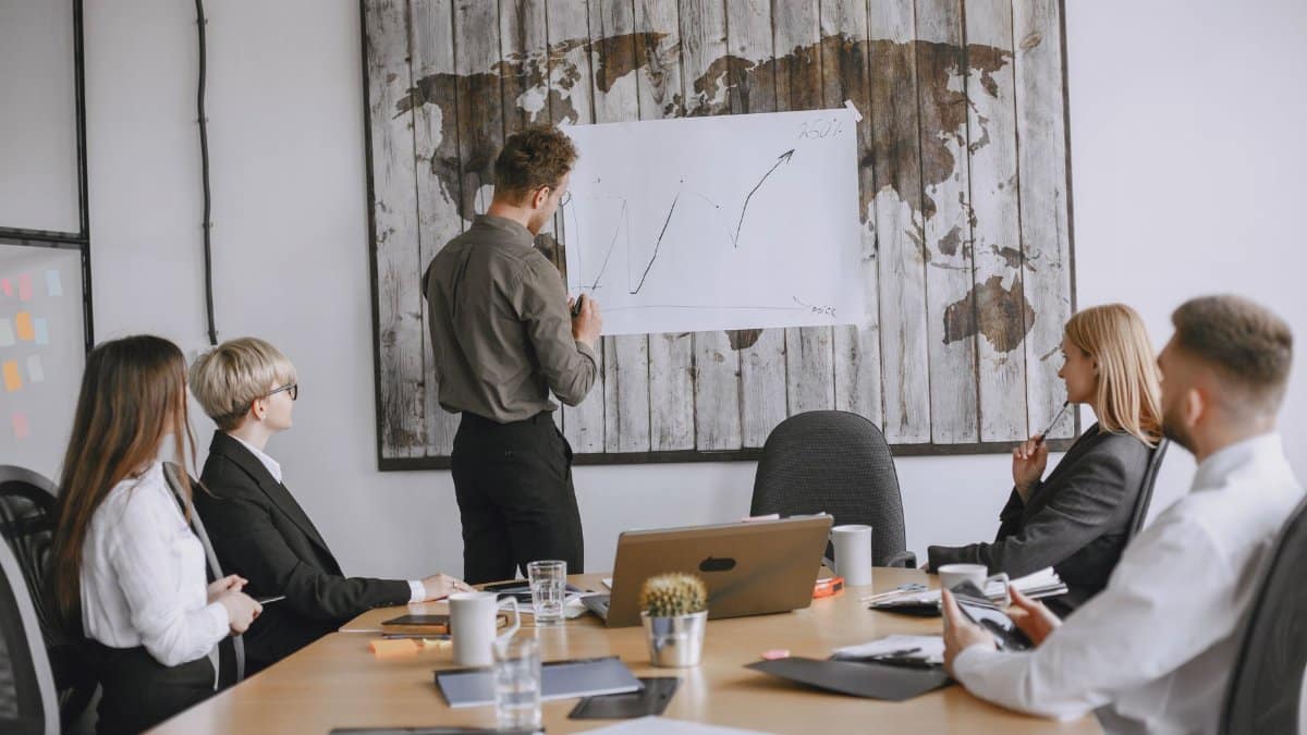 Group of business professionals discussing strategies with growth chart in conference room.