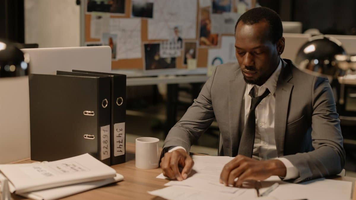 Man in business suit working late at office desk with documents and files.