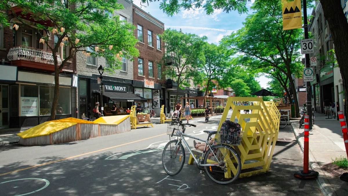 A lively street scene in Montreal with people enjoying a sunny day, cycling and walking.