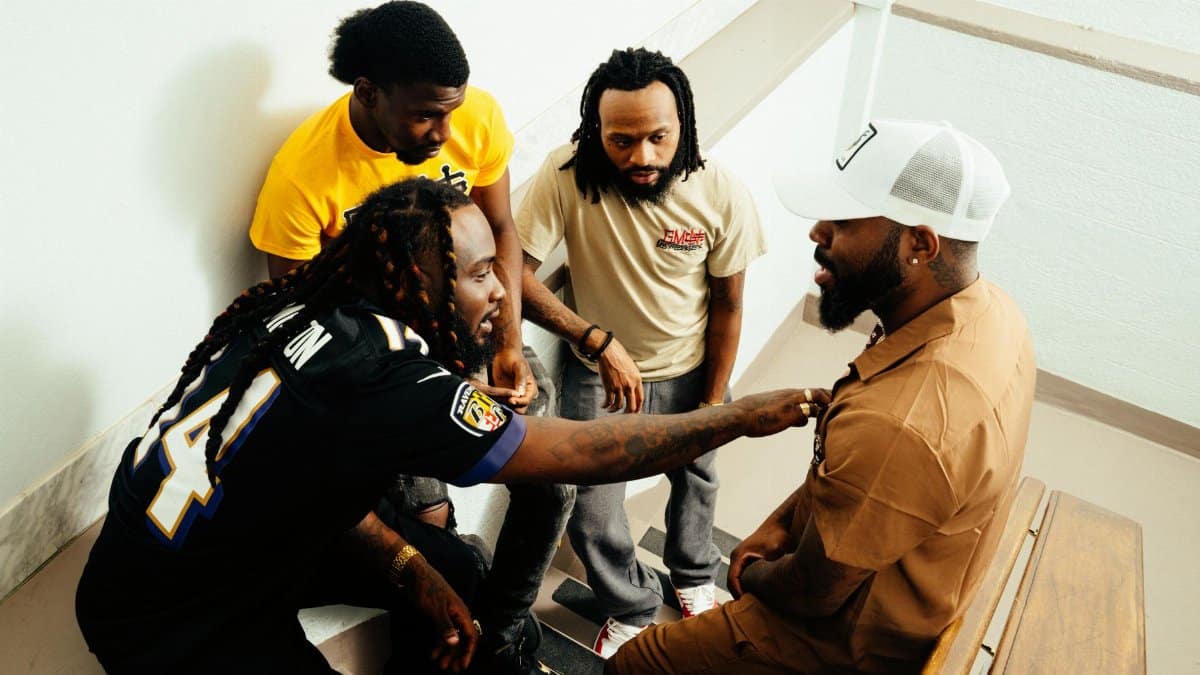A group of men engaging in conversation on an indoor staircase, balancing casual and warm interactions.