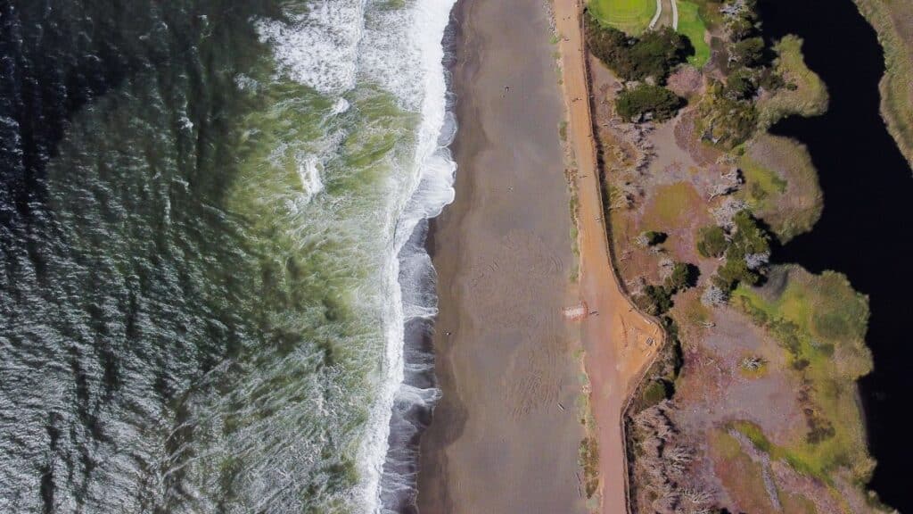 Stunning aerial shot of Pacifica Beach, California, with waves crashing onto the shore.