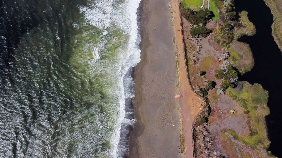 Stunning aerial shot of Pacifica Beach, California, with waves crashing onto the shore.