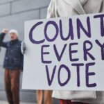 Protesters holding signs and chanting for fair vote count during a winter rally.