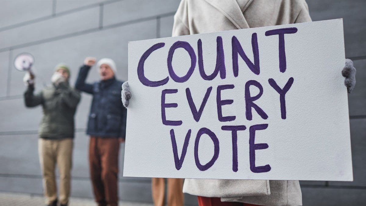 Protesters holding signs and chanting for fair vote count during a winter rally.