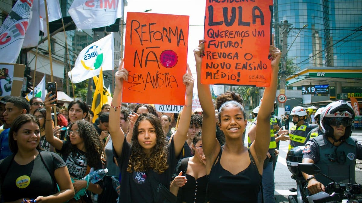 Youth-led street protest with signs advocating educational reform and political change.