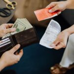 Close-up of a financial transaction involving cash and receipts over a coffee table.