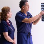 Two healthcare professionals in scrubs examining a medical x-ray image, discussing diagnosis.