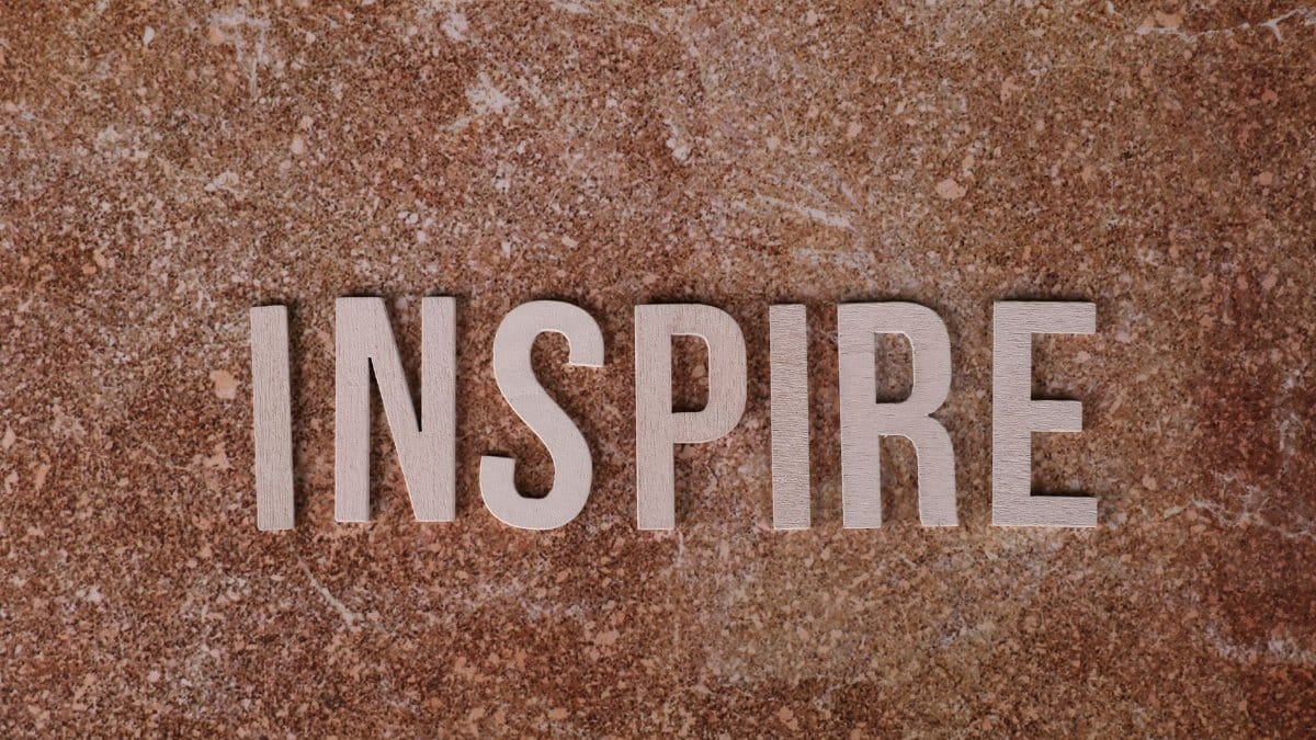 Inspirational word 'INSPIRE' on a textured stone background for motivation.