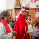 Catholic priest in traditional vestments during a religious ceremony in a church setting.