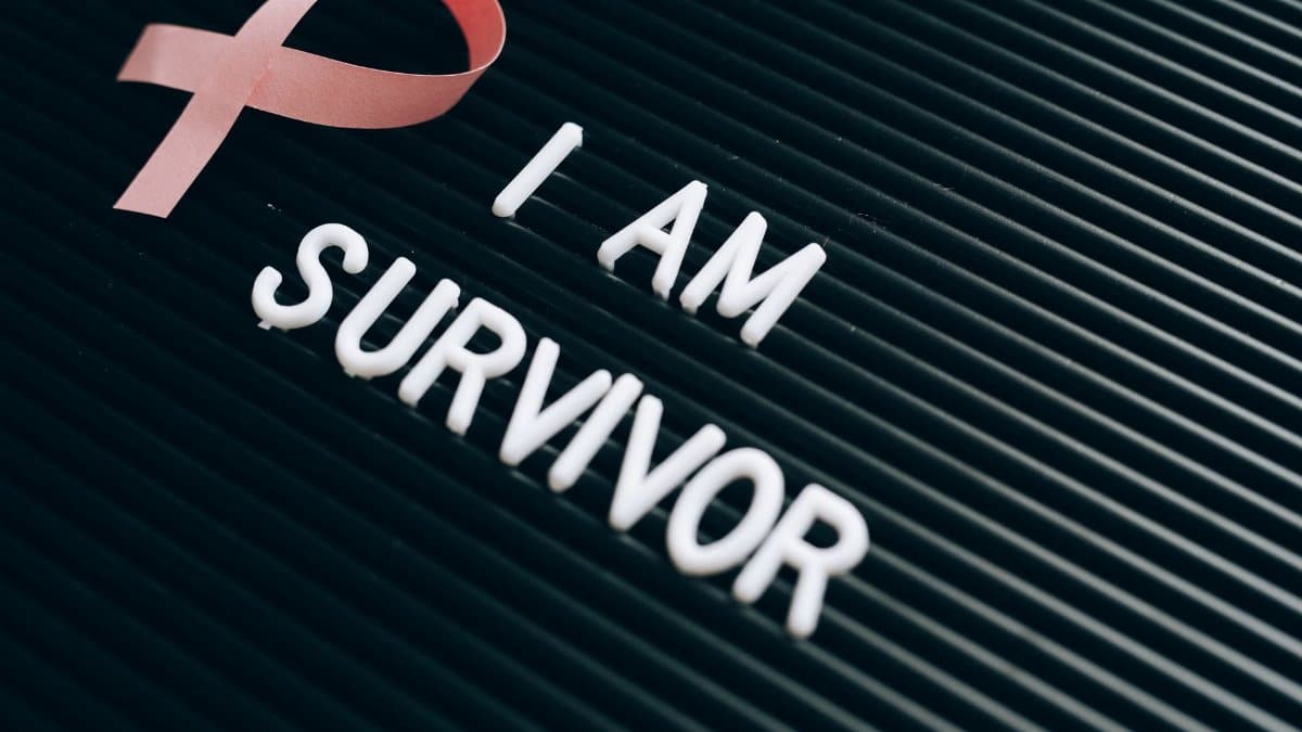 Breast cancer survivor message with pink ribbon and empowering text on board.