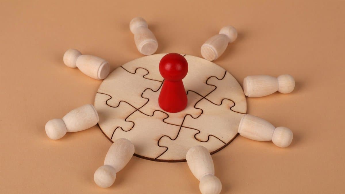 Wooden puzzle with a red pawn symbolizing leadership and teamwork dynamics.