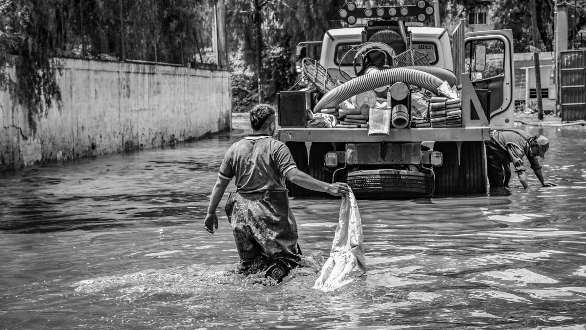 A black and white photo depicting flood cleanup efforts in an urban setting, showcasing resilience.