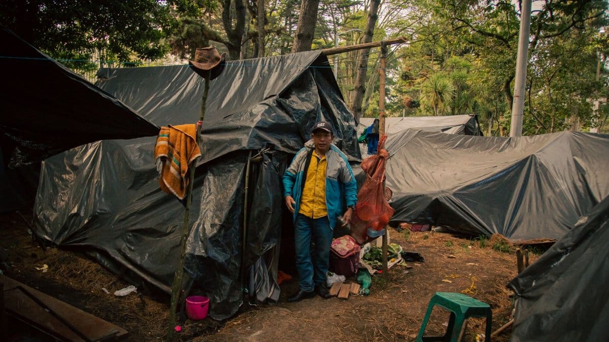 A man stands in a makeshift tent in a forest in Bogota, Colombia.