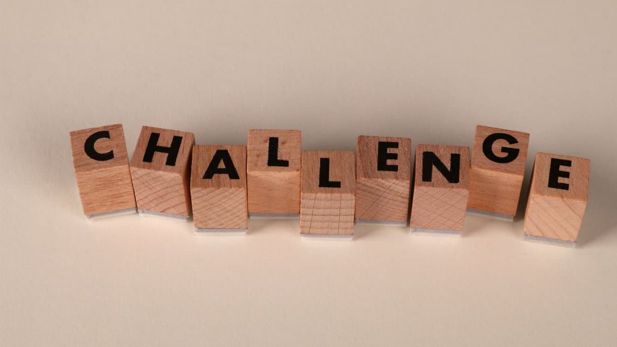 Wooden blocks arranged to spell 'Challenge' against a neutral backdrop, symbolizing overcoming obstacles.