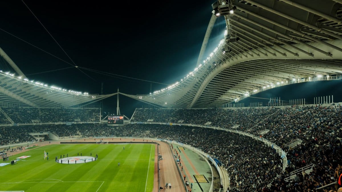 A crowded soccer stadium under bright lights at night, capturing the excitement of a live sports event.