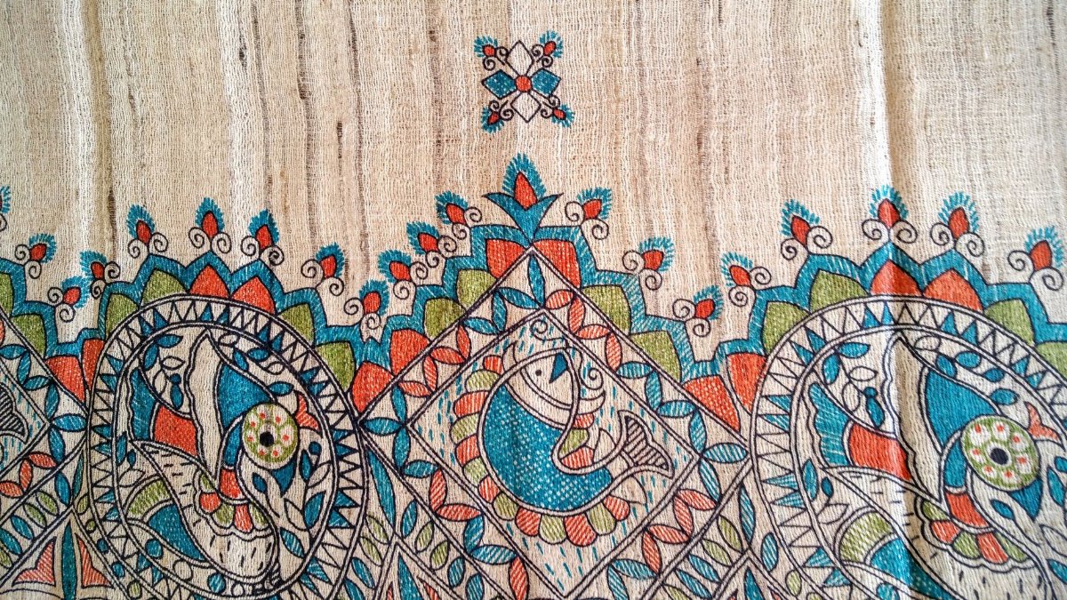 Colorful traditional fabric art featuring fish motifs and intricate patterns on canvas.